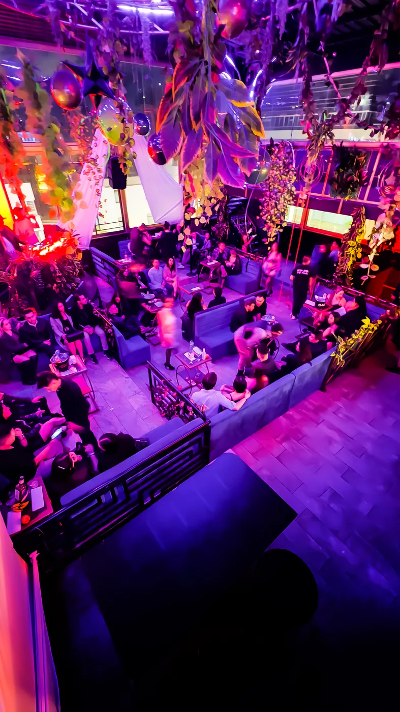 Salón lleno durante una Fiesta Spicy en Bogotá, entre luces moradas y rosadas