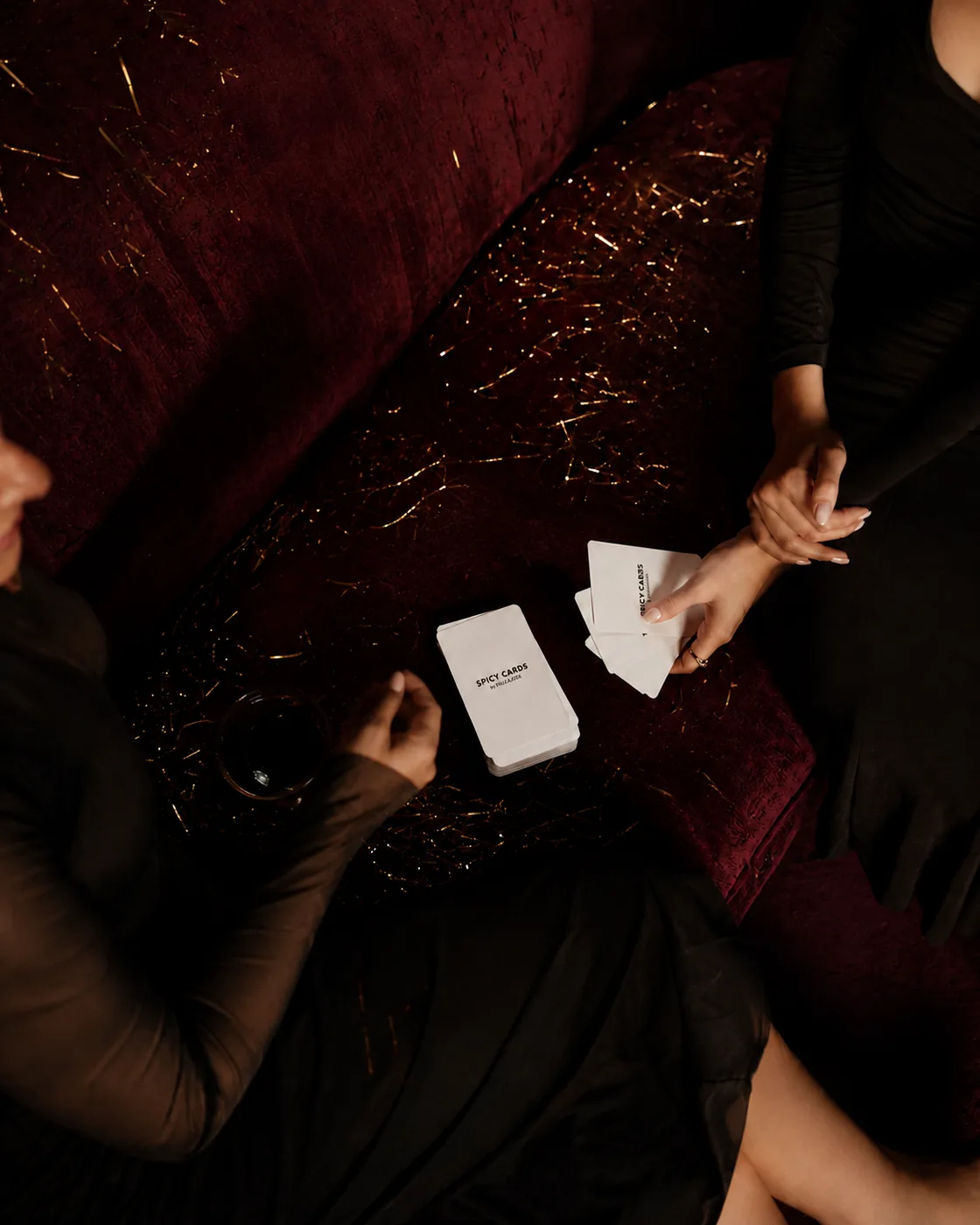 Manos sosteniendo cartas del juego Spicy Cards en una mesa