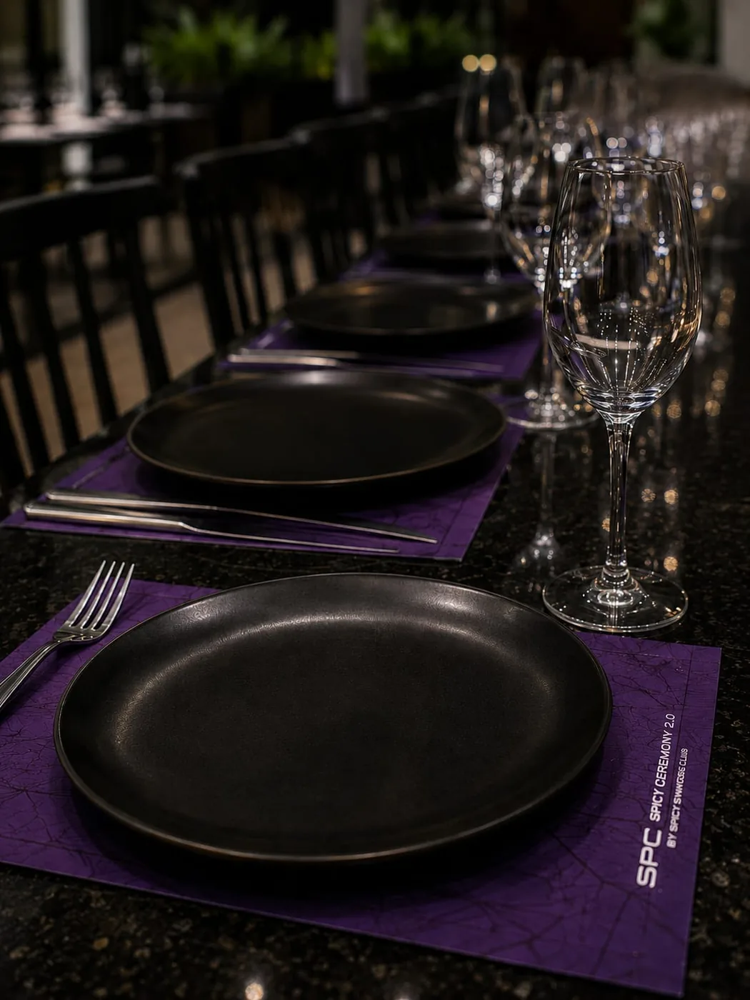 Mesa larga servida con vajilla negra y cristalería para una Cena Spicy